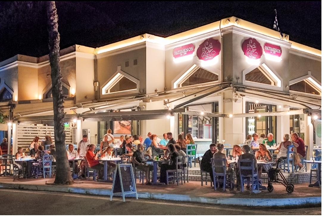 Guests dining under the lit awning of El Greco Leros on a warm summer evening